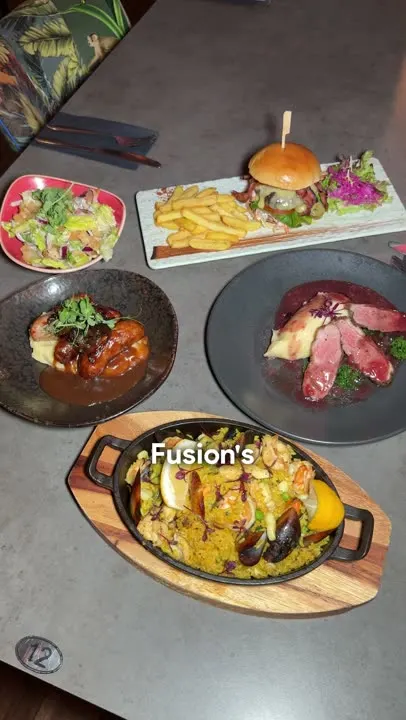 A table of dishes from Geisha Fusion’s new menu: paella, duck, a burger and salad